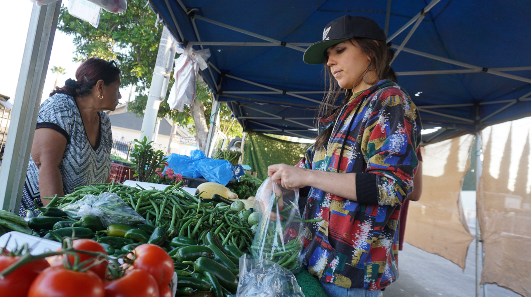 Shopper selecting fresh produce at a vendor stall at the Lincoln Heights Farmers Market