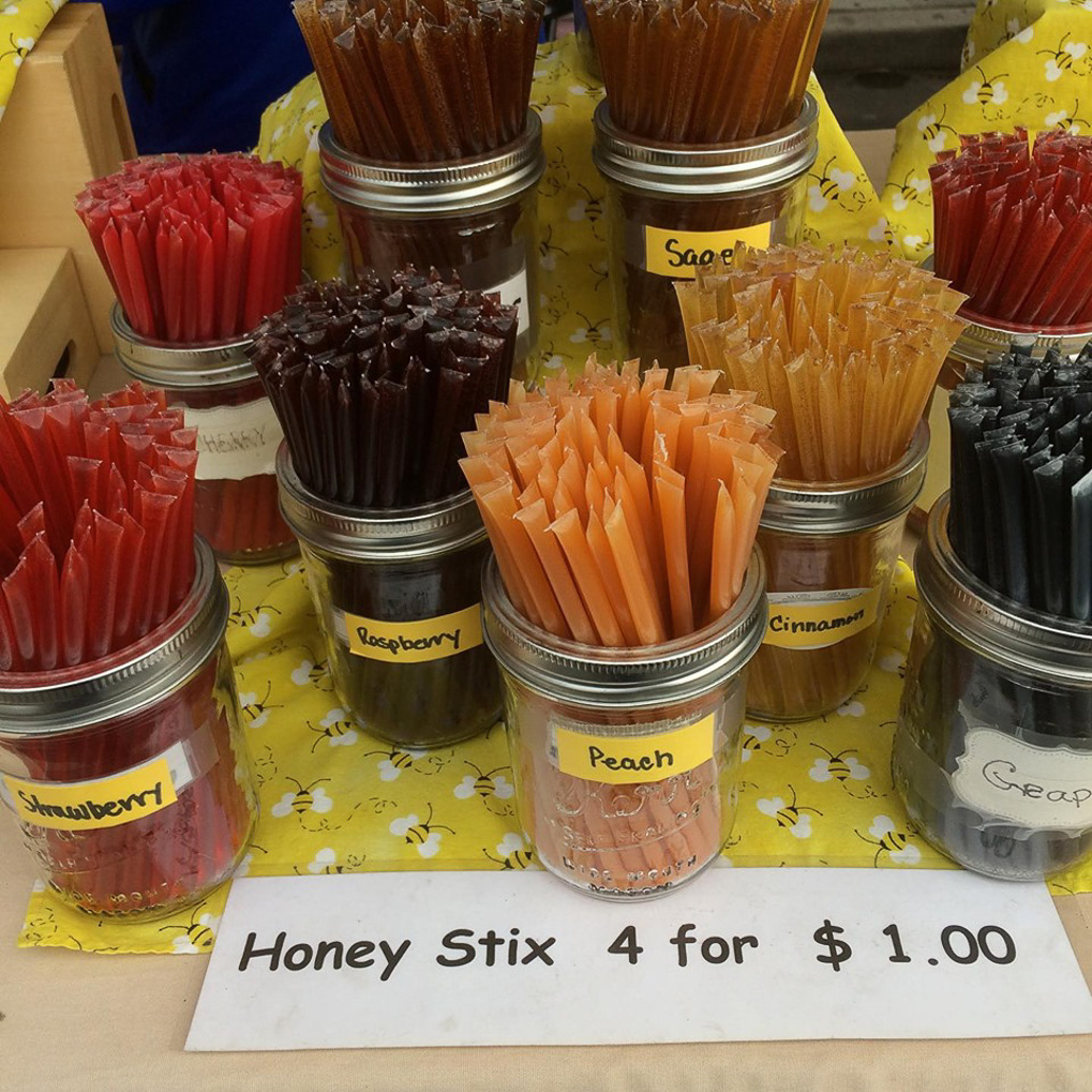 Colorful honey stix in mason jars — strawberry, raspberry, peach, sage, cinnamon, grape flavors